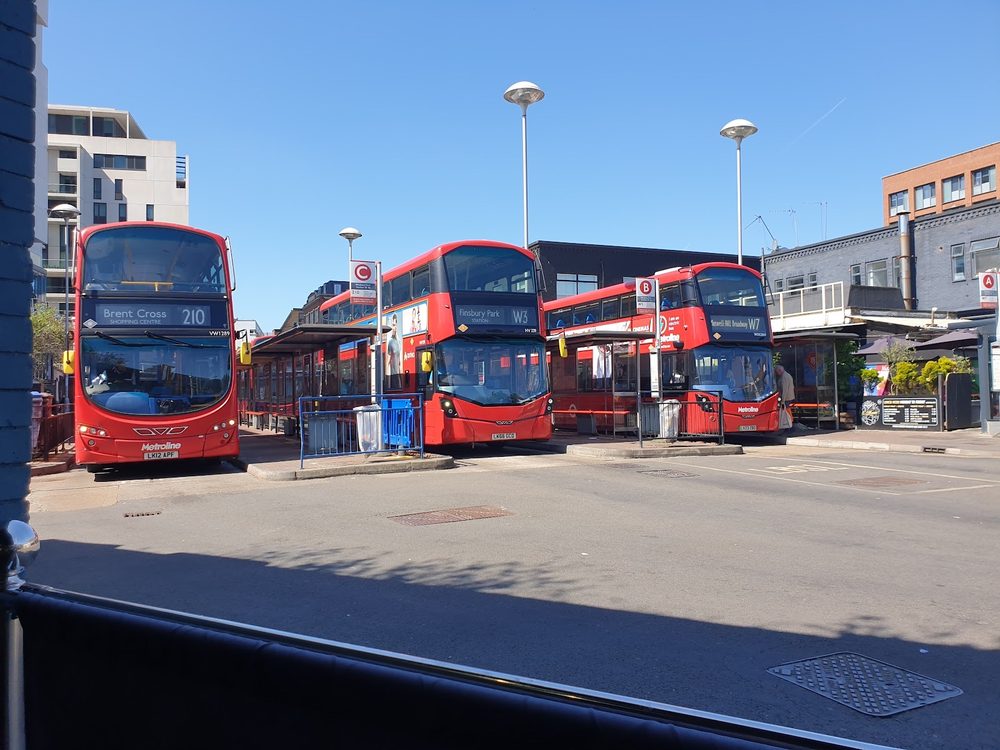 The view from a cafe window across the bus station forecourt, red double-deckers under a blue sky