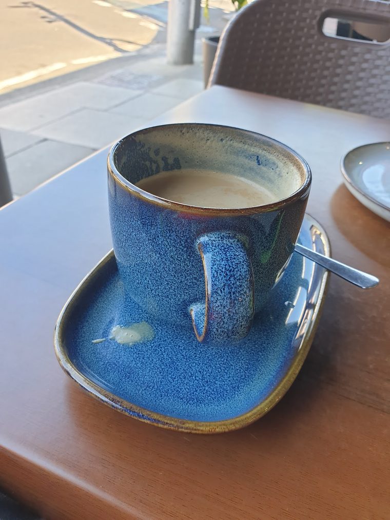 A flat white in a hand-thrown blue speckled cup and saucer